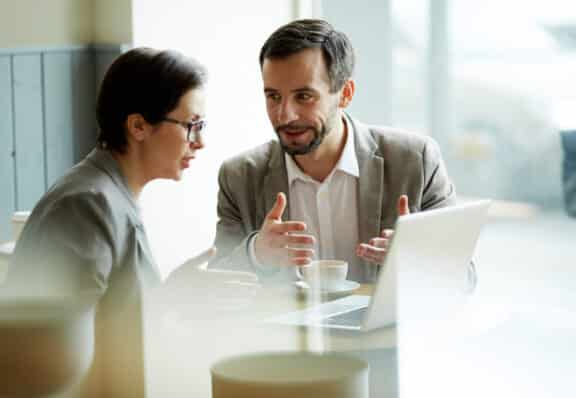 Young employees having discussion of online project in cafe