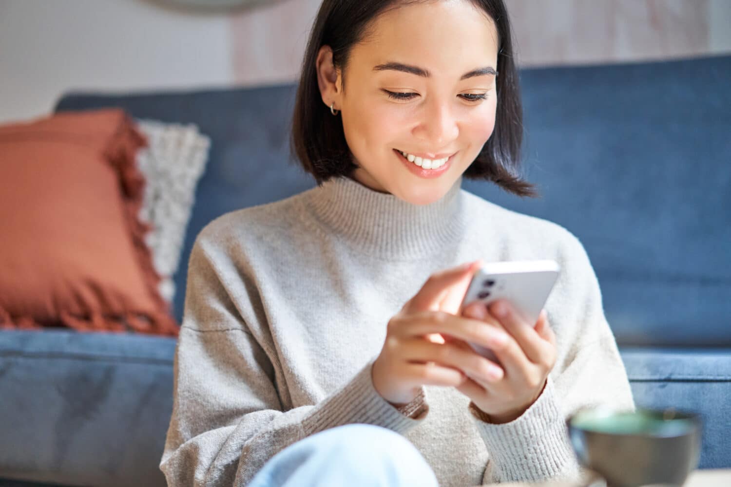 Smiling woman using her mobile phone at home, illustrating a seamless omnichannel insurance customer experience