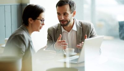 Young employees having discussion of online project in cafe