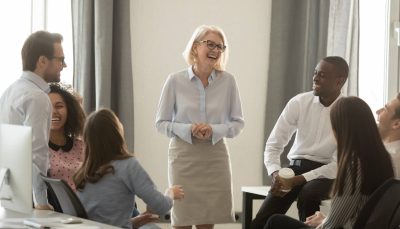 Laughing,Old,Coach,Team,Leader,Talking,With,Diverse,Coworkers,Chatting